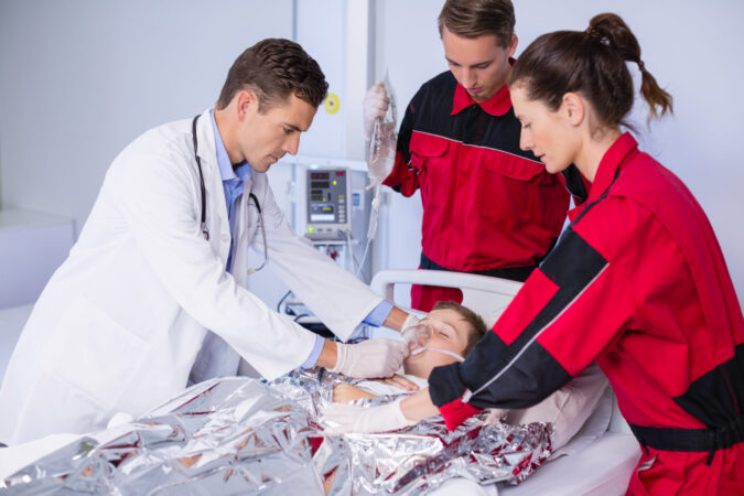 Doctor and paramedics examining a patient in emergency room at hospital